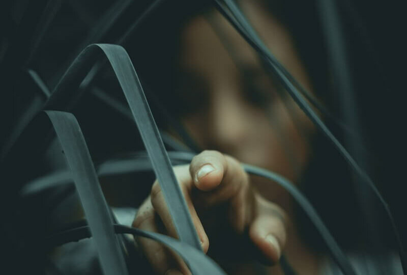 woman in gray shirt behind plant